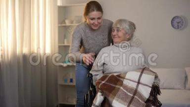 女志愿者用格子呢的老残疾妇女轻轻地覆盖在养老院里